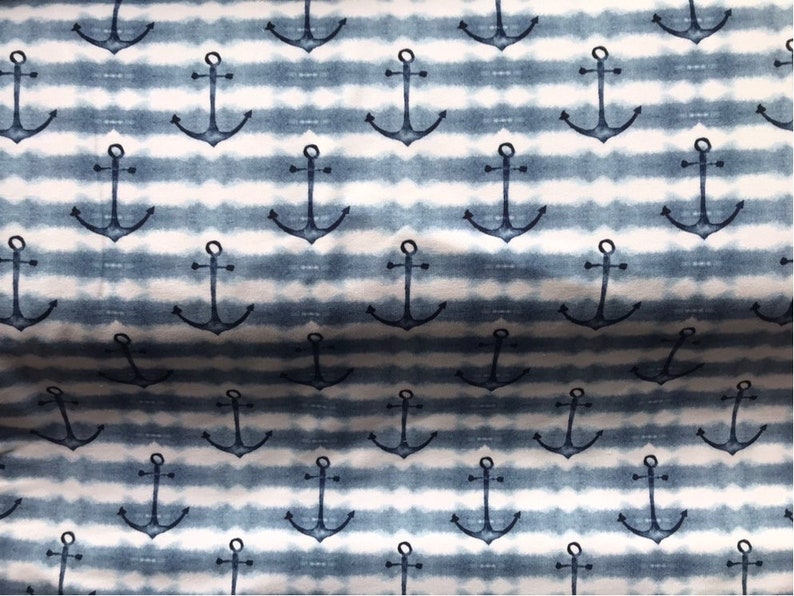 May include: A white and blue striped fabric with a repeating pattern of navy blue anchors. The fabric has a tie-dye effect.