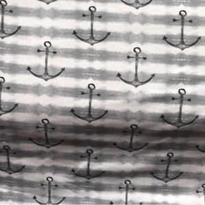 May include: A white and gray fabric with a repeating pattern of black anchor designs. The anchors are stylized and have a watercolor effect.