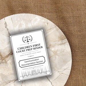 May include: A white binder titled "CHILDREN FIRST COURT PREP BINDER" with a scales of justice graphic. The binder includes a "Communication Documentation Section" label. The binder is on a marble-patterned surface with a burlap background.