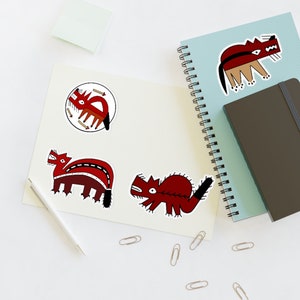 May include: Four red and black stylized animal stickers on a white background. The stickers are of a wolf, a bear, a fox, and a deer. The stickers are all in a similar style, with black outlines and red and black details.