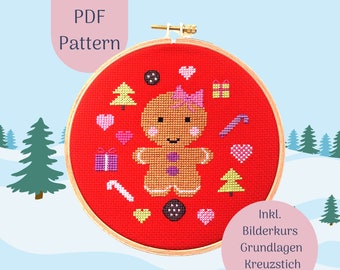 May include: A cross-stitch pattern featuring a gingerbread person with a pink bow, surrounded by Christmas-themed icons on a red background. The text "PDF Pattern" is at the top. The design is set in a wooden embroidery hoop.