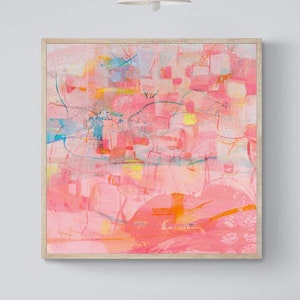 May include: A framed abstract painting with pink, orange, yellow, and blue colors. The painting is hanging on a light gray wall above a white step stool and a white couch with pink and cream pillows.
