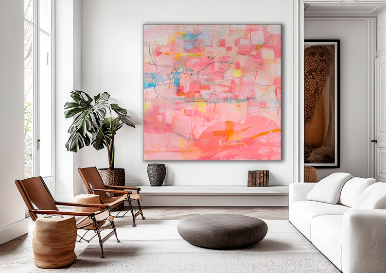 May include: Abstract painting with pink, orange, yellow, and blue hues. The painting is framed and hanging on a white wall in a living room setting.