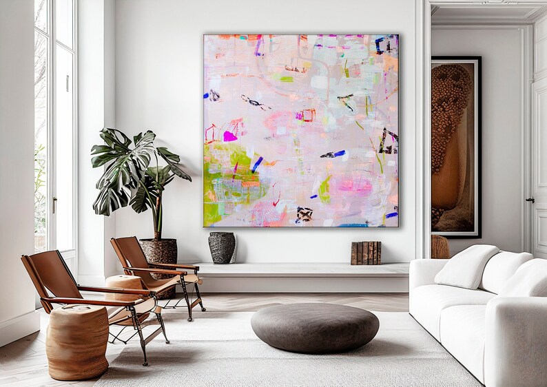 Peut inclure: Peinture abstraite aux couleurs rose, verte, bleue et blanche. La peinture est accroch&eacute;e &agrave; un mur blanc dans un salon avec un canap&eacute; blanc, deux fauteuils en cuir marron et une plante en pot.
