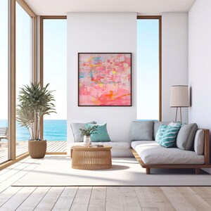 May include: A white couch with a light pink abstract painting on the wall behind it. The couch has a wooden frame and is situated in a room with large windows overlooking the ocean.