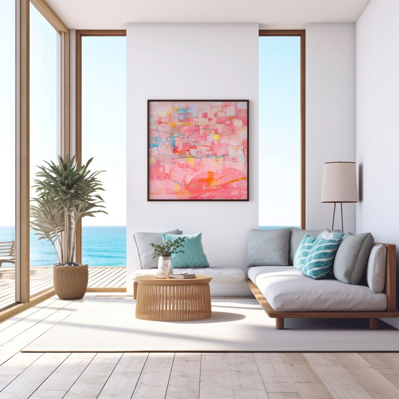 May include: A white couch with a light pink abstract painting on the wall behind it. The couch has a wooden frame and is situated in a room with large windows overlooking the ocean.