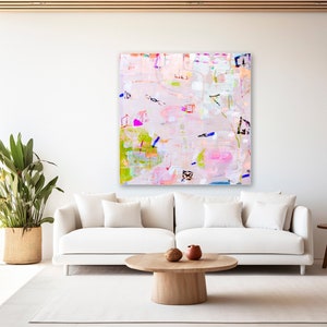 Peut inclure: Peinture abstraite aux couleurs rose, verte, bleue et blanche. La peinture est sur une toile blanche et est accroch&eacute;e &agrave; un mur blanc dans un salon.