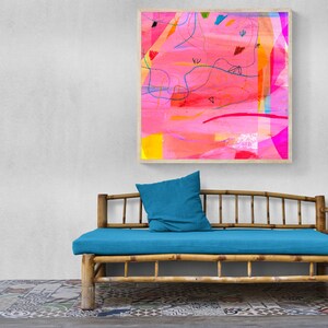 May include: A blue cushion sits on a bamboo daybed with a colorful abstract painting hanging on the wall behind it.