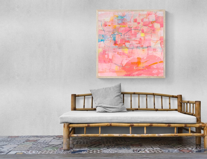May include: A light pink abstract painting in a wooden frame hangs above a light gray cushioned daybed with a bamboo frame.