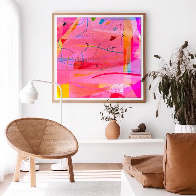 May include: Abstract art print with a pink, yellow, blue, and red color scheme. The print is framed in a natural wood frame and is hanging on a white wall.