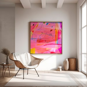 May include: Abstract painting with pink, yellow, blue, and red colors. The painting is framed in a light wood frame and is hanging on a white wall in a living room setting.