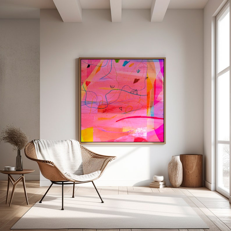 May include: Abstract painting with pink, yellow, blue, and red colors. The painting is framed in a light wood frame and is hanging on a white wall in a living room setting.
