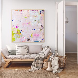 Peut inclure: Un canap&eacute; gris clair avec une couverture ray&eacute;e et deux coussins. Un tableau abstrait encadr&eacute; avec des couleurs rose, verte et bleue est accroch&eacute; au mur derri&egrave;re le canap&eacute;.