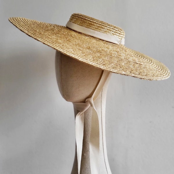 Wide brimmed straw boater hat with cream coloured ribbons