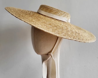 Wide brimmed straw boater hat with cream coloured ribbons