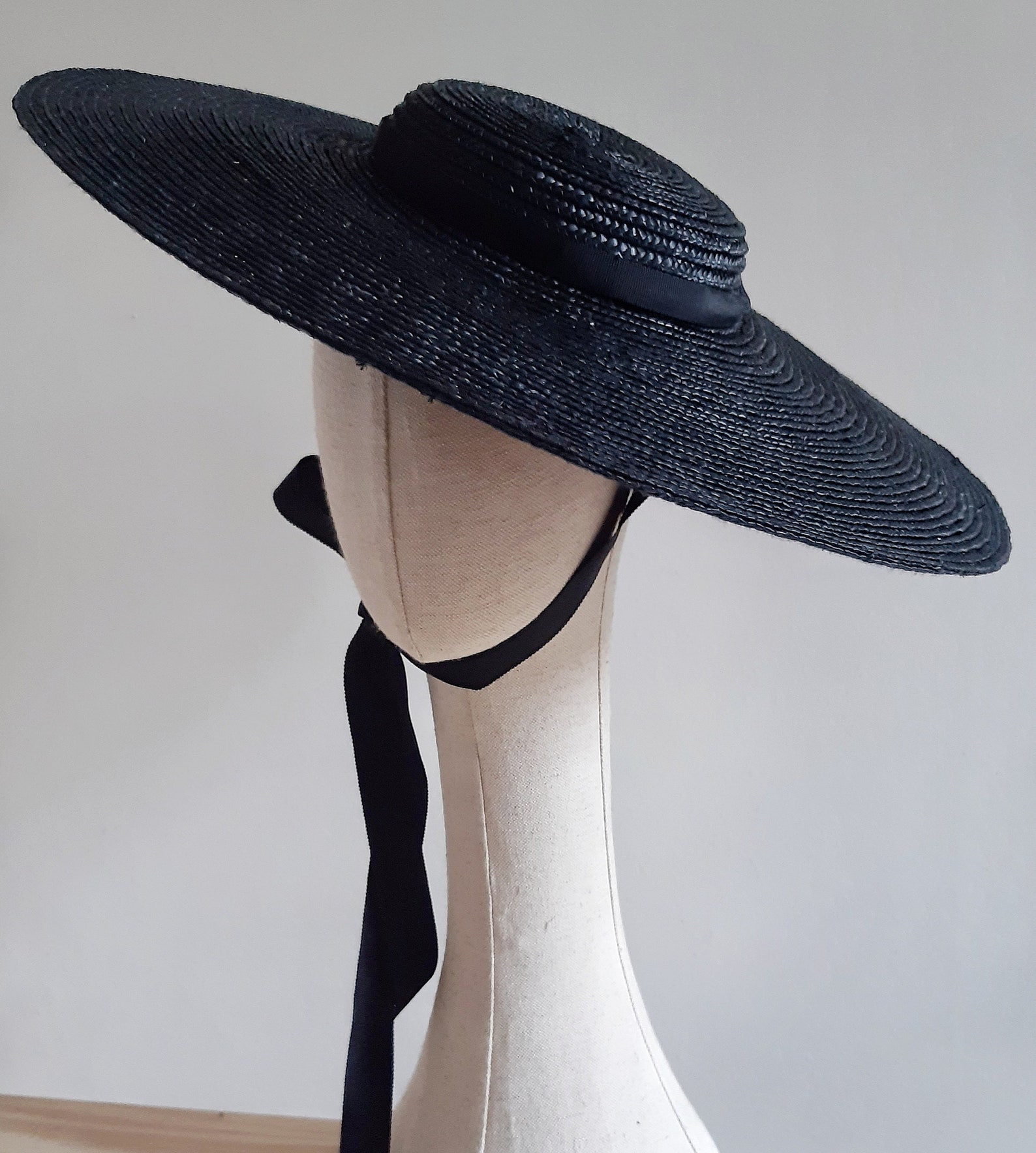 Black straw sun hat with flat crown and chin ribbon, blending Victorian flair with summer goth elegance.