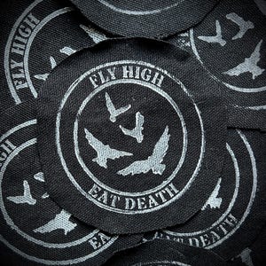 May include: A collection of black circular patches with a white graphic design. The design includes the words "FLY HIGH" and "EAT DEATH" in a circular pattern, with stylized bird illustrations in the center.