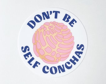 Puede incluir: Una pegatina redonda blanca con texto azul que dice "No seas un conchas egoísta" y una ilustración de pastelería concha rosa y amarilla en el centro.