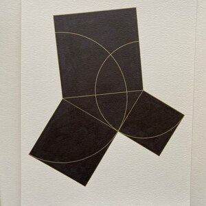 May include: A black geometric shape with gold lines. The shape is made up of three squares that are connected at the corners. The squares are arranged in a way that creates a three-dimensional effect.