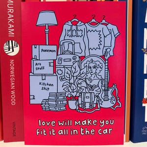 May include: A red greeting card featuring a light blue illustration of moving boxes, clothing, a lamp, a guitar, and a woman's portrait. The text "love will make you fit it all in the car" is at the bottom.