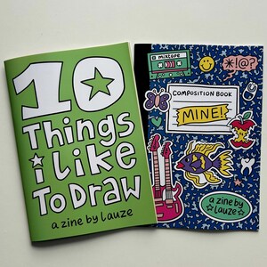 May include: Two zines are displayed. The green zine cover reads "10 Things I Like To Draw" and "a zine by Lauze." The blue zine cover says "COMPOSITION BOOK MINE!" and features a fish, guitars, and other graphics.