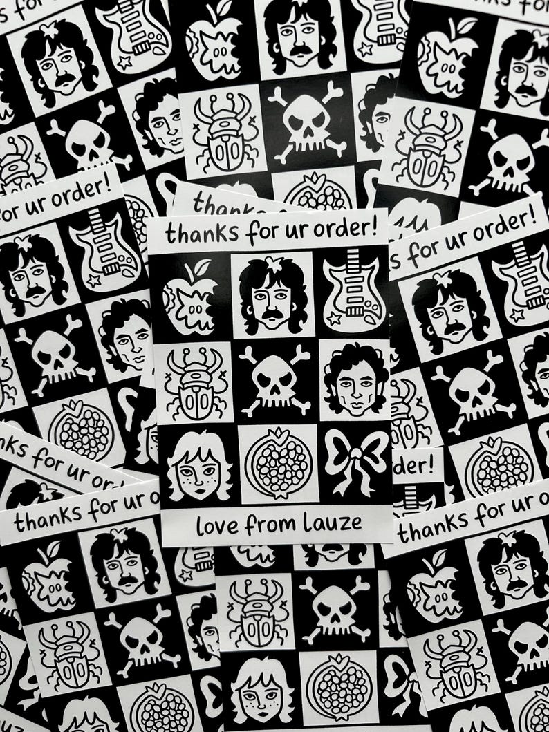 May include: A collection of black and white stickers with various illustrations, including faces, skulls, guitars, and apples. Some stickers have the text "thanks for ur order!" and "love from Lauze".