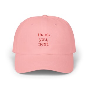 Könnte beinhalten: Rosafarbene Baseballkappe mit dem Text "thank you, next." in rot gestickt.