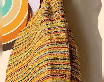 May include: A yellow tote bag with horizontal stripes in red, black, and blue. The bag has brown straps and is displayed on a mannequin. The background features a retro-style design with curved lines in various colors.