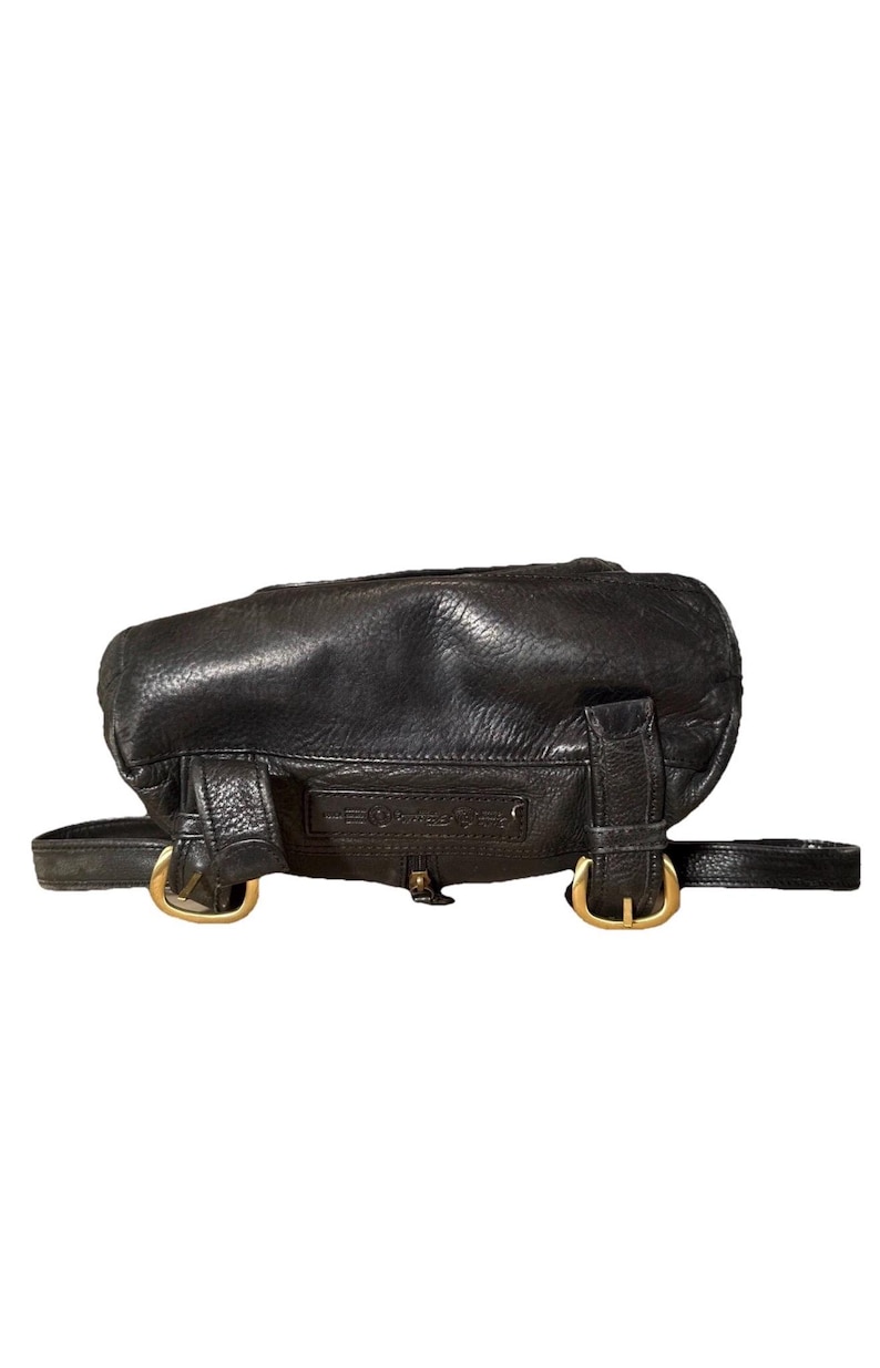 May include: Black leather backpack with gold-colored buckles and hardware. The bag has a rounded shape and adjustable straps. The leather appears to be slightly distressed, giving it a vintage look. The bag has a small zipper closure.