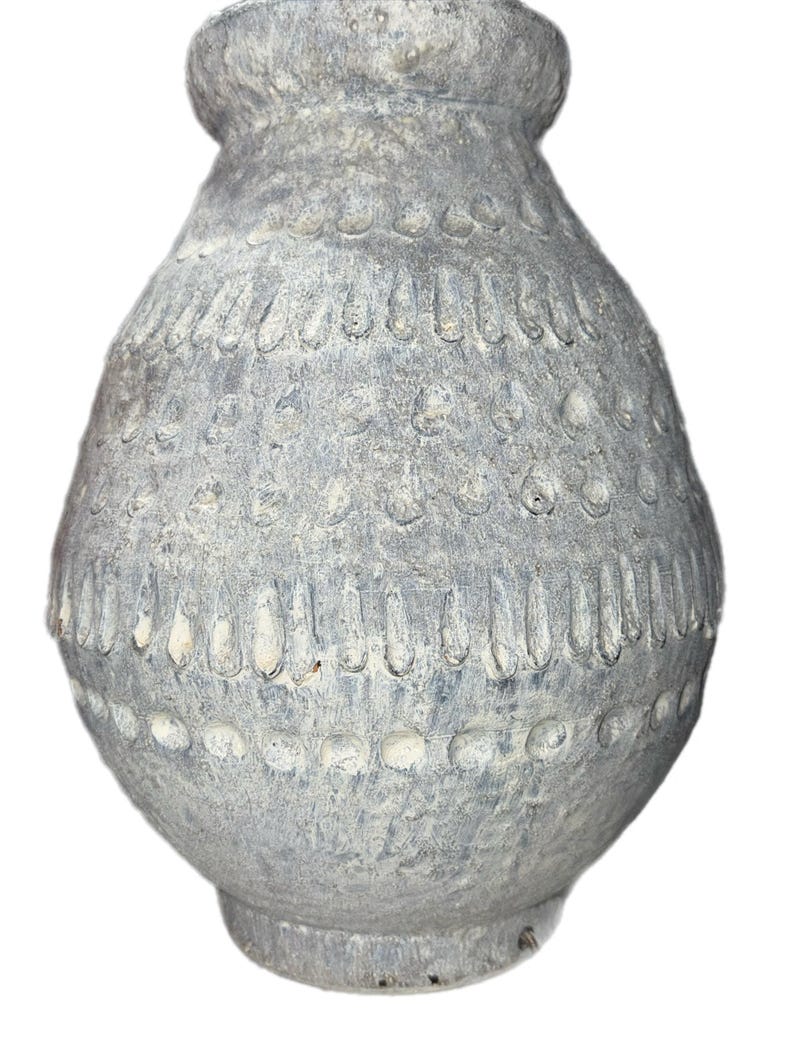 May include: A gray decorative vase with a textured surface and a bulbous body. The vase features a series of vertical and circular patterns around the body. The vase has a wide base and a narrow neck.