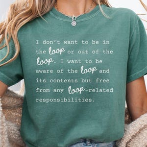 May include: Light green t-shirt with the text "I don't want to be in the loop or out of the loop. I want to be aware of the loop and its contents but free from any loop-related responsibilities." The shirt is a short-sleeved, casual style.