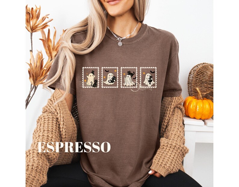 May include: Espresso-colored t-shirt featuring a Halloween-themed design. The design includes four postage stamp-style images with cartoon ghosts and black cats. The word "ESPRESSO" is printed in large white letters at the bottom of the shirt.