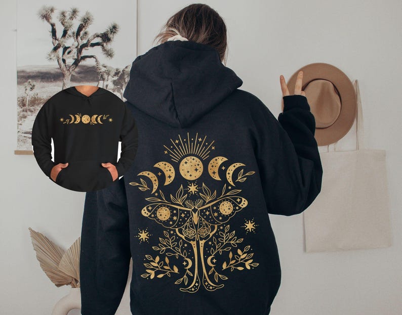 May include: Black hoodie with a gold celestial design on the back, featuring moons, stars, and a moth. The front of the hoodie has a smaller gold design of moon phases. The hoodie has a hood and a front pocket.