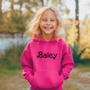 May include: A pink hooded sweatshirt with the name "Bailey" in a black, stylized font on the front.