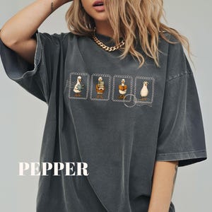 May include: Dark gray oversized t-shirt with a graphic of four cartoon geese on postage stamps. The word "PEPPER" is printed in white block letters at the bottom of the shirt.