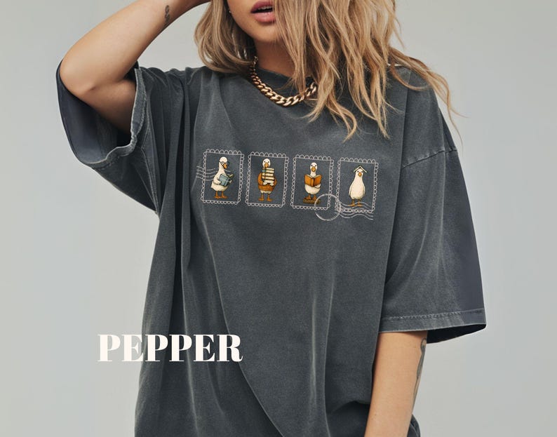 May include: Dark gray oversized t-shirt with a graphic of four cartoon geese on postage stamps. The word "PEPPER" is printed in white block letters at the bottom of the shirt.