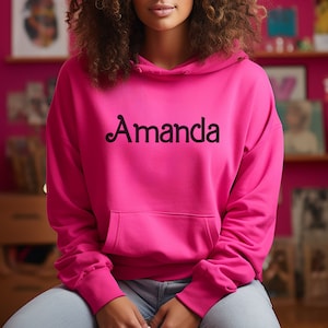 May include: A bright pink hoodie with a black cursive font that says "Amanda" on the front.