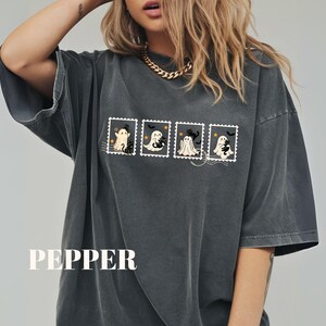 May include: Dark gray oversized t-shirt featuring a Halloween-themed design. The design includes four postage stamp illustrations with cartoon ghosts and a black cat. The word "PEPPER" is printed at the bottom.