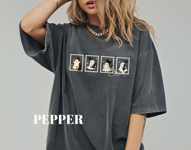 May include: Dark gray oversized t-shirt featuring a Halloween-themed design. The design includes four postage stamp illustrations with cartoon ghosts and a black cat. The word "PEPPER" is printed at the bottom.