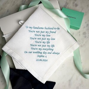 May include: A white square handkerchief featuring teal embroidered text that reads: To my handsome husband-to-be, You're not just my friend, You're my love, You're not just my love, You're my life, You're not just my life, You're my everything, On our wedding day and always, Sophia x, 22.06.2024.