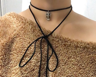 May include: A brown fuzzy off-the-shoulder sweater with a black choker necklace and a silver owl pendant.