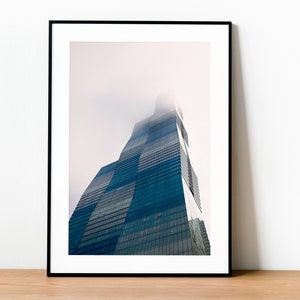 May include: A tall, modern skyscraper with a glass facade, partially obscured by fog or clouds. The building is angled upwards, creating a dramatic perspective.