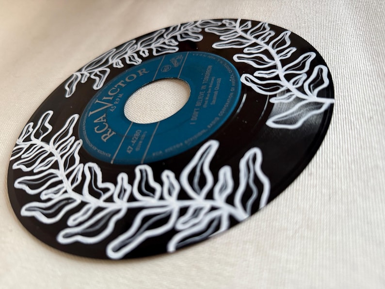 May include: A black vinyl record with a white fern design painted on it. The label is blue and says "RCA VICTOR" and "I Don't Believe In Tomorrow".