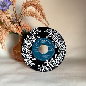 May include: A black vinyl record with a white fern design painted on it. The record is labeled "RCA Victor" and "47-4280". The song title "I Don't Believe In Tomorrow" is printed on the record.