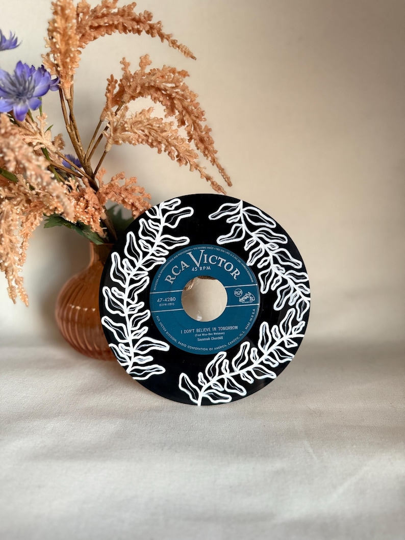 May include: A black vinyl record with a white fern design painted on it. The record is labeled "RCA Victor" and "47-4280". The song title "I Don't Believe In Tomorrow" is printed on the record.