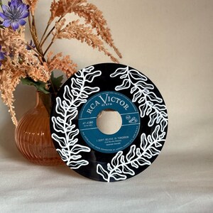May include: A black vinyl record with white painted fern designs. The record label is RCA Victor 45 RPM and the song title is "I Don't Believe In Tomorrow" by Savannah Churchill.