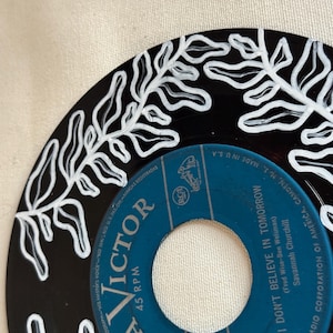 May include: A black vinyl record with a white fern design painted around the edge. The label is blue and says "Victor 45 RPM" and "I Don't Believe in Tomorrow" by Savannah Churchill.