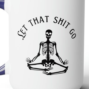 Peut inclure: Mug en céramique blanche avec une anse et un intérieur bleu marine. Le mug présente le texte "LET THAT SHIT GO" autour d'un squelette noir en position de yoga.