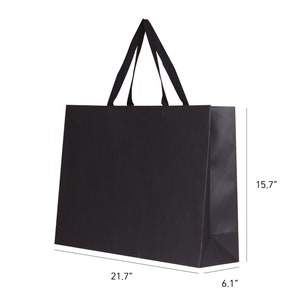 May include: A black shopping bag with a rectangular shape and a pair of black handles. The bag is 21.7 inches long, 15.7 inches high, and 6.1 inches wide. The bag is made of a matte material.
