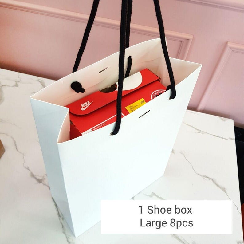 May include: A white paper shopping bag with black rope handles. Inside the bag is a red Nike shoe box. The bag has the text "1 Shoe box Large 8pcs" at the bottom.